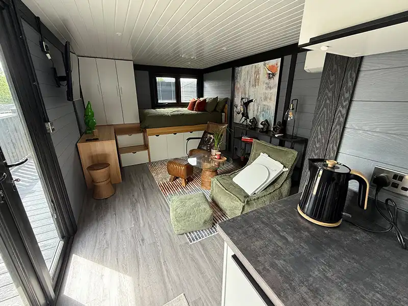 Living area inside a finished annexe with a sofa, tall storage and a kitchen worktop