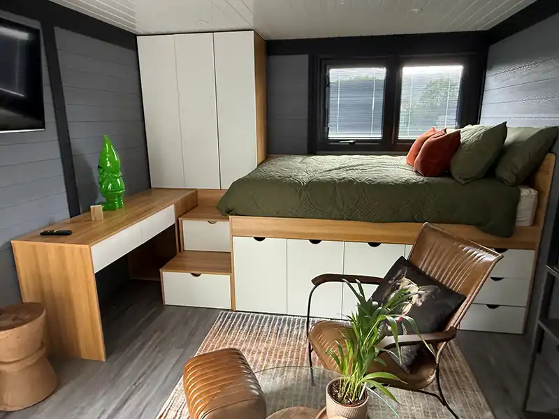Bedroom inside a finished annexe with a raised bed, built-in drawers and a desk