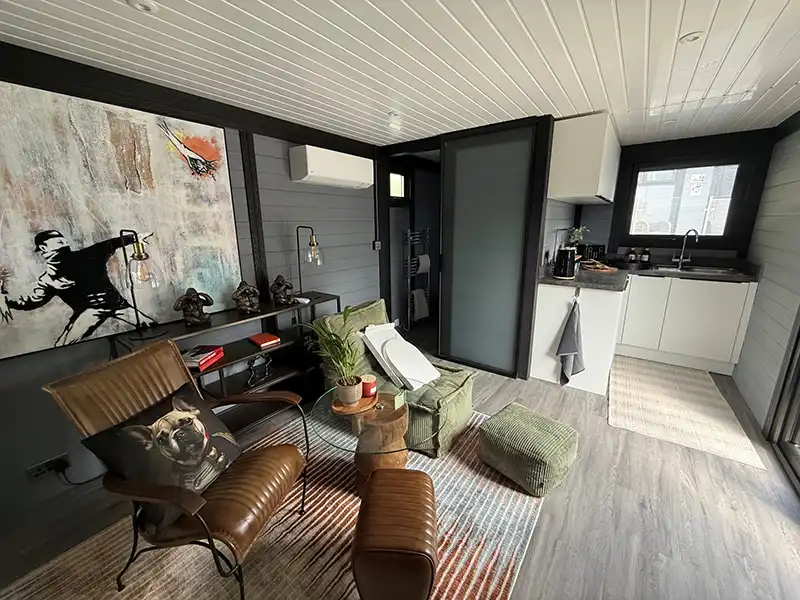 Open plan lounge and kitchen inside a finished annexe with leather armchairs