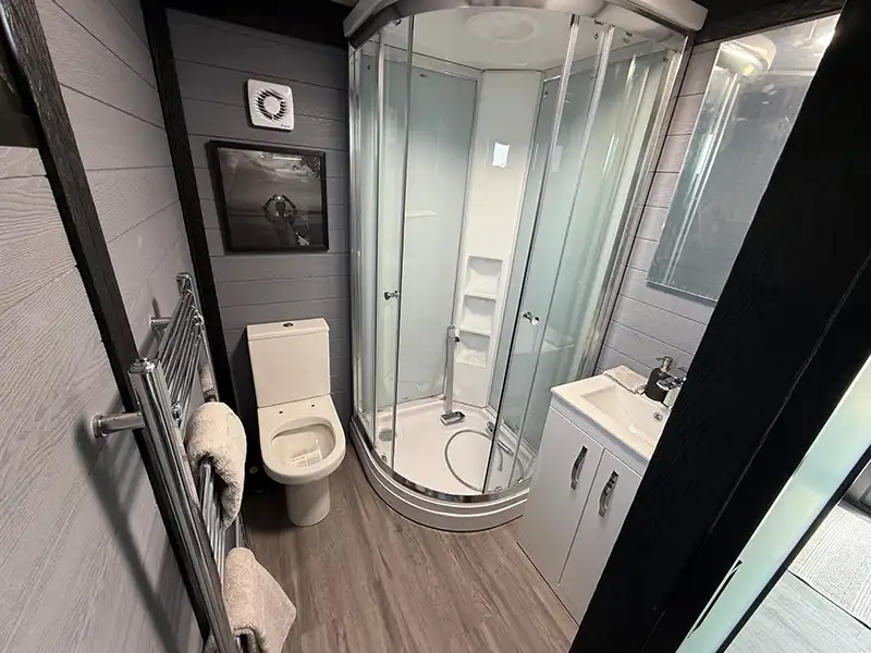 Shower room inside a finished annexe with a corner shower, toilet, basin and towel rail