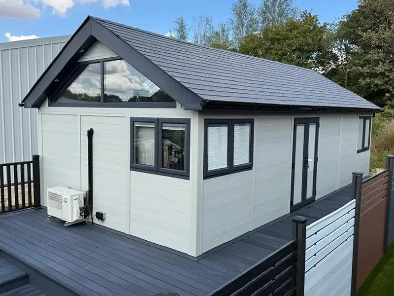 Grey composite annexe with a glazed gable end, a dark pitched roof and a composite deck