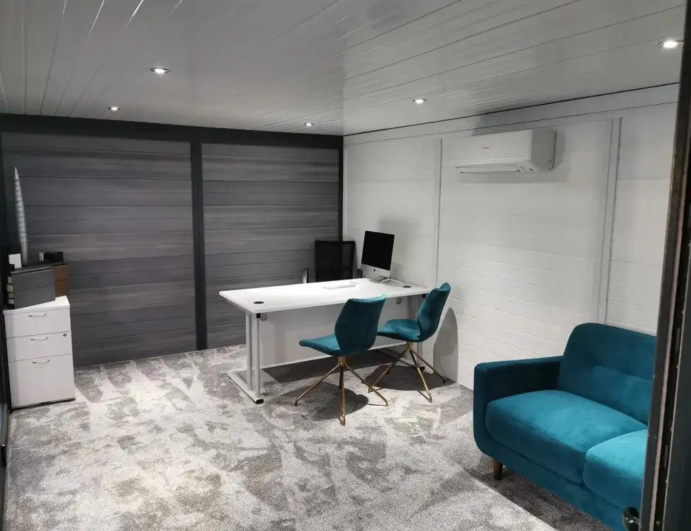 Composite garden office with white desk and teal sofa